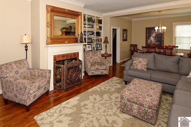 living room with dark hardwood / wood-style floors, built in features, ornamental molding, a chandelier, and a tile fireplace