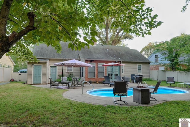 back of property featuring a fenced in pool, a yard, a fire pit, and a patio