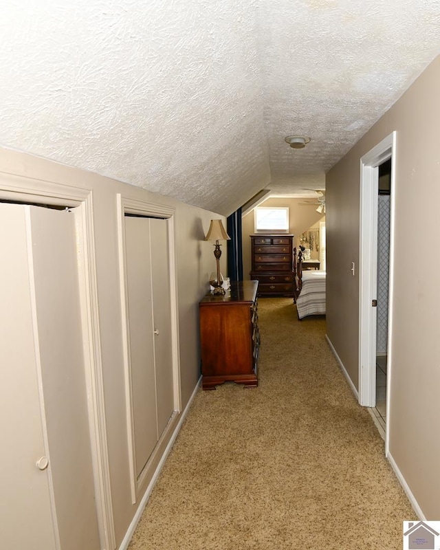 corridor with carpet, a textured ceiling, and lofted ceiling