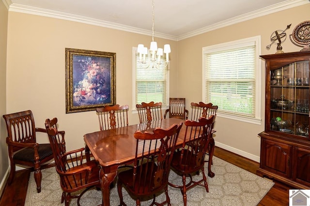 dining area with wood-type flooring, an inviting chandelier, and ornamental molding