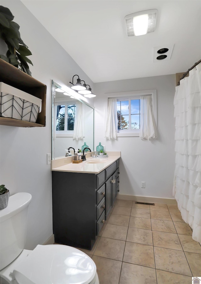 bathroom featuring a healthy amount of sunlight, toilet, tile patterned flooring, and vanity