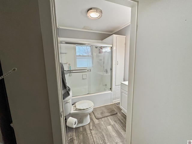 bathroom with toilet, enclosed tub / shower combo, ornamental molding, and wood-type flooring