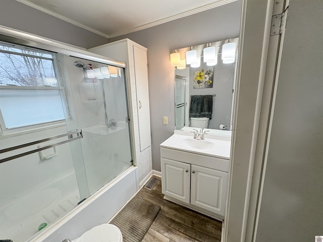 full bathroom with crown molding, hardwood / wood-style flooring, toilet, shower / bath combination with glass door, and vanity