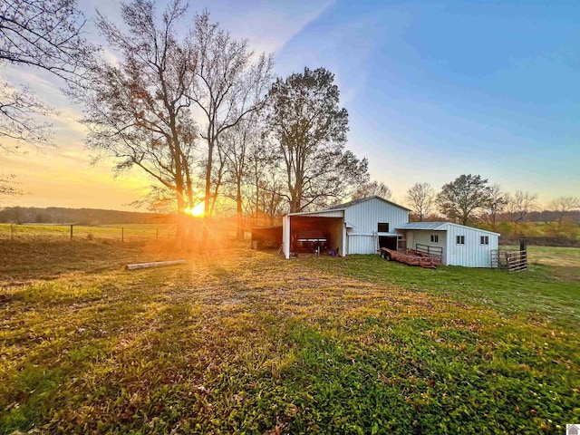 yard at dusk featuring an outdoor structure and a rural view