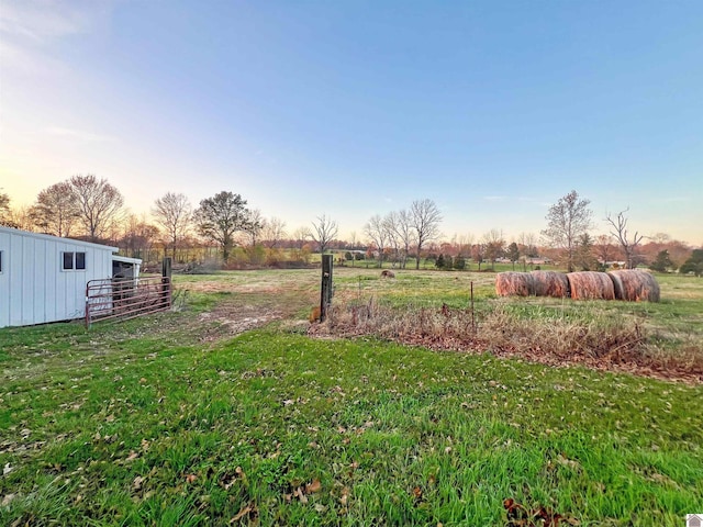 yard at dusk featuring a rural view