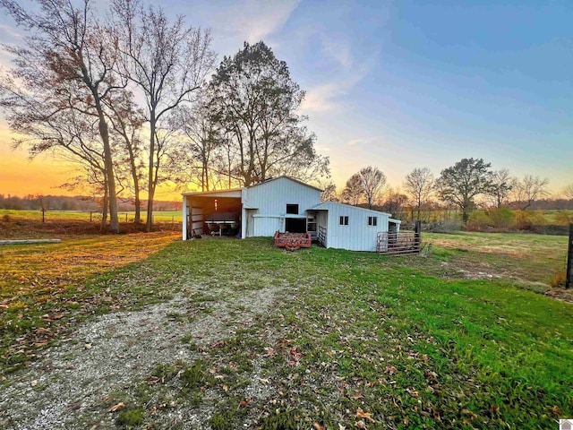 back house at dusk featuring a yard, an outdoor structure, and a rural view