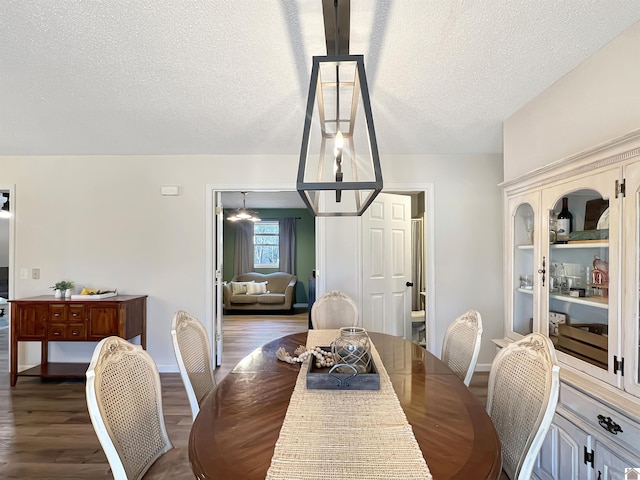 dining space featuring a textured ceiling and dark hardwood / wood-style floors