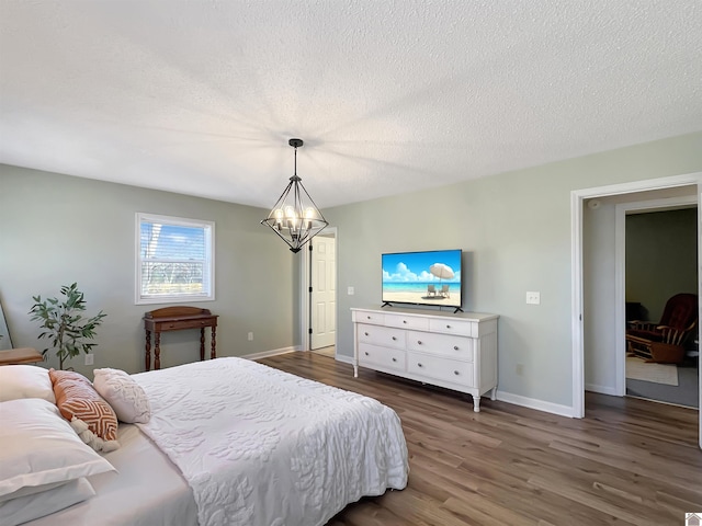 bedroom featuring a textured ceiling, dark hardwood / wood-style flooring, and an inviting chandelier