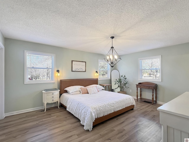 bedroom with hardwood / wood-style floors, an inviting chandelier, and a textured ceiling