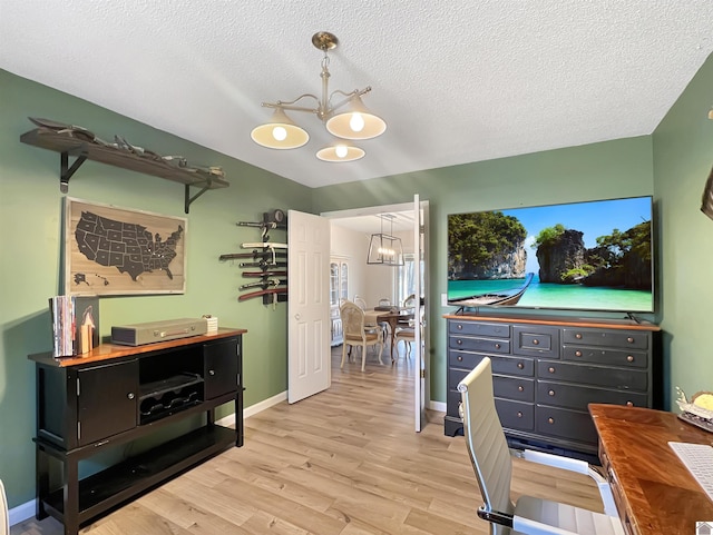 home office featuring a textured ceiling, an inviting chandelier, and light hardwood / wood-style flooring