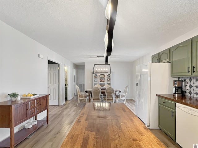 kitchen with white appliances, a textured ceiling, green cabinets, and light wood-type flooring