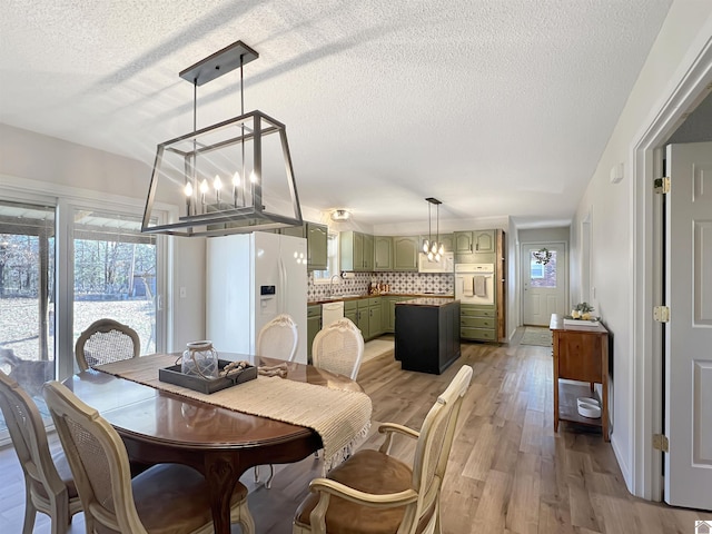 dining area with sink, hardwood / wood-style floors, a chandelier, and a textured ceiling