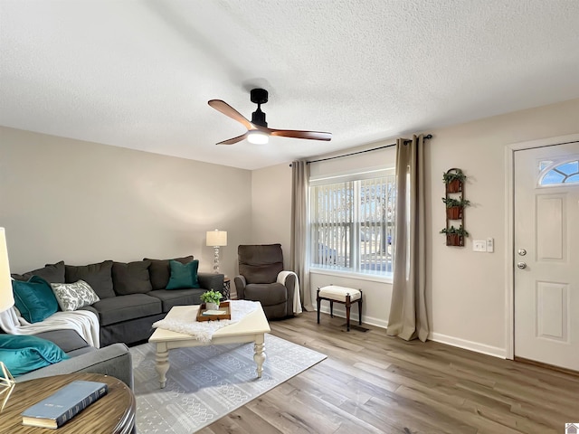 living room featuring ceiling fan, hardwood / wood-style floors, and a textured ceiling