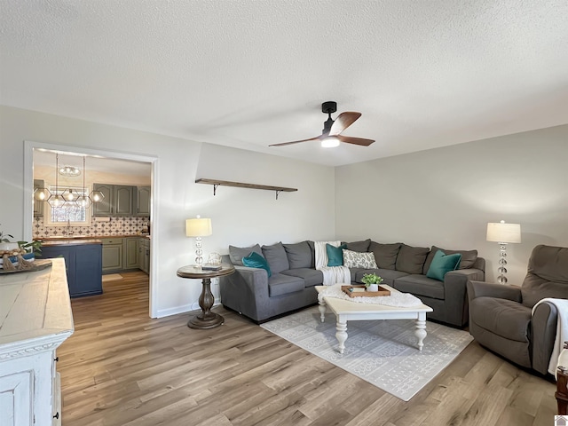 living room with sink, light hardwood / wood-style floors, a textured ceiling, and ceiling fan