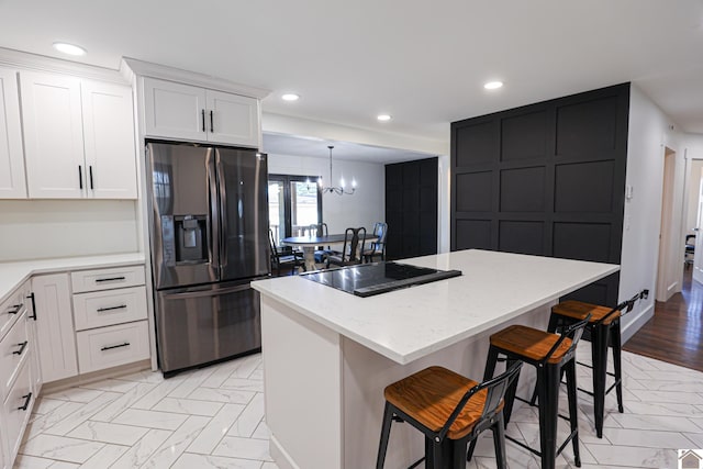 kitchen featuring stainless steel refrigerator with ice dispenser, white cabinetry, and a center island