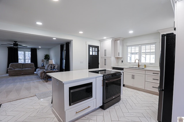 kitchen with white cabinetry, electric stove, sink, black fridge, and built in microwave