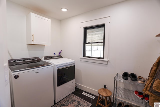 clothes washing area with dark tile patterned flooring, cabinets, and washer and clothes dryer