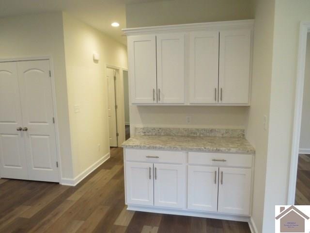 kitchen featuring light stone countertops, white cabinetry, and dark hardwood / wood-style flooring