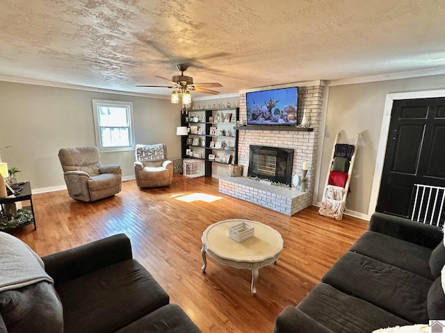 living room featuring hardwood / wood-style flooring, crown molding, a fireplace, and a textured ceiling