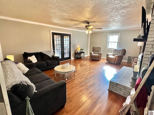 living room with french doors, a textured ceiling, ornamental molding, ceiling fan, and hardwood / wood-style floors