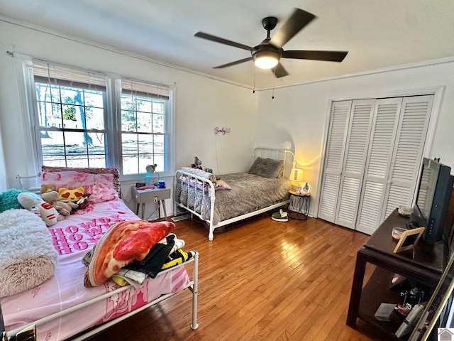 bedroom with crown molding, hardwood / wood-style floors, ceiling fan, and a closet