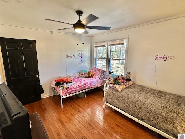 bedroom featuring wood-type flooring, ornamental molding, and ceiling fan