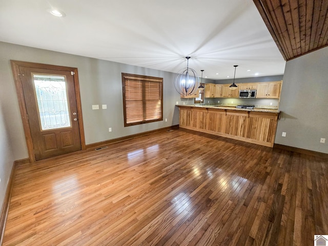 kitchen featuring light brown cabinetry, hanging light fixtures, a notable chandelier, kitchen peninsula, and light wood-type flooring