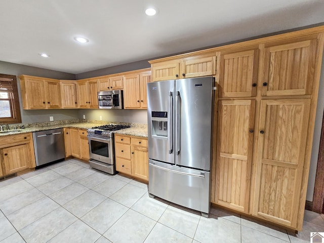 kitchen featuring light stone countertops, light tile patterned floors, stainless steel appliances, and sink