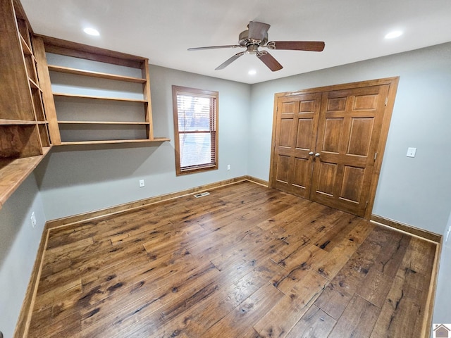 unfurnished bedroom featuring dark wood-type flooring, a closet, and ceiling fan