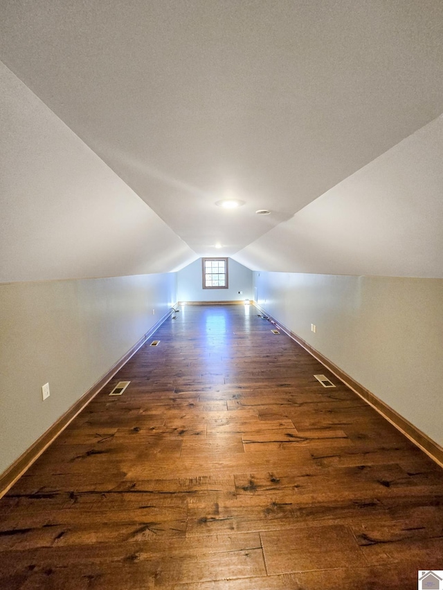 additional living space featuring vaulted ceiling and dark hardwood / wood-style floors