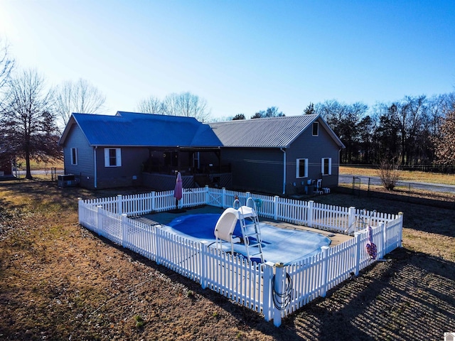 back of house with metal roof, a patio area, a fenced in pool, and fence