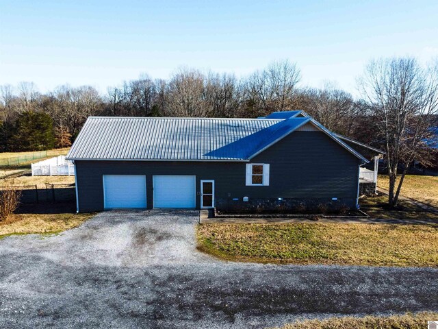 single story home with an attached garage, driveway, and metal roof