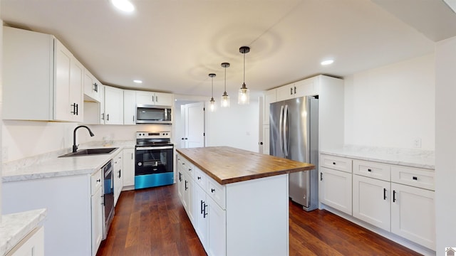 kitchen with wood counters, sink, stainless steel appliances, and white cabinets