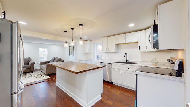 kitchen with sink, wooden counters, white cabinetry, stainless steel appliances, and a kitchen island