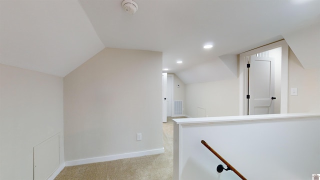 hall featuring vaulted ceiling and light colored carpet