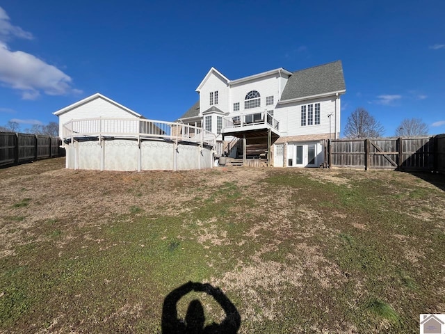 rear view of property featuring a fenced in pool and a lawn