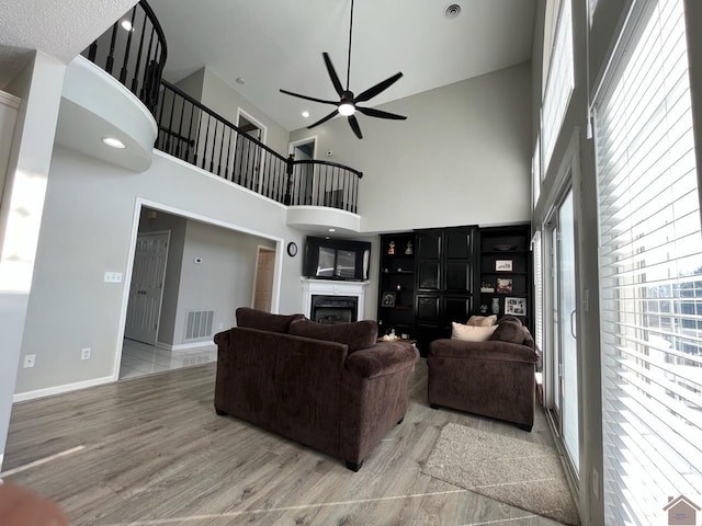 living room featuring hardwood / wood-style floors, ceiling fan, and a high ceiling