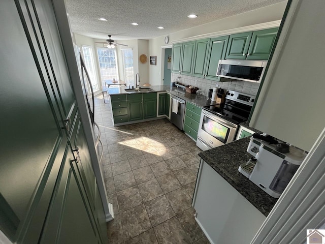 kitchen with appliances with stainless steel finishes, sink, kitchen peninsula, and green cabinets