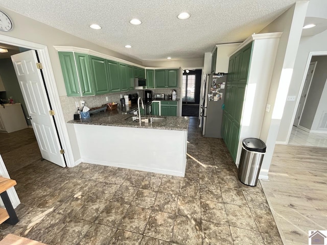 kitchen featuring sink, stainless steel refrigerator, green cabinets, stone countertops, and kitchen peninsula