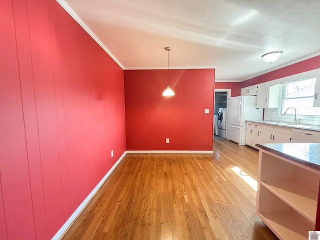 kitchen featuring white cabinetry, light hardwood / wood-style flooring, white refrigerator, pendant lighting, and independent washer and dryer