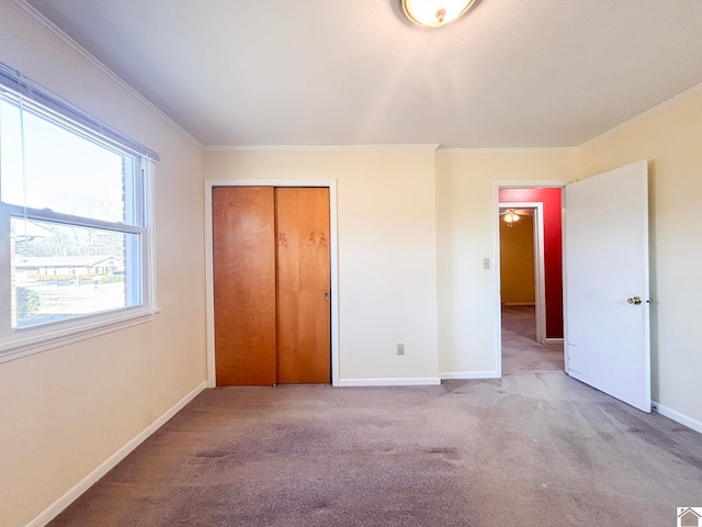 unfurnished bedroom with crown molding, light carpet, and a closet