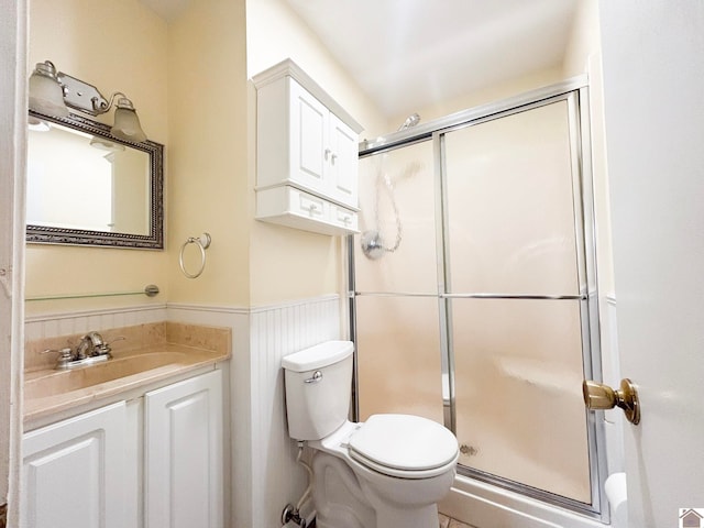 bathroom with vanity, a shower with door, and toilet