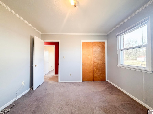 unfurnished bedroom featuring crown molding, light colored carpet, and a closet