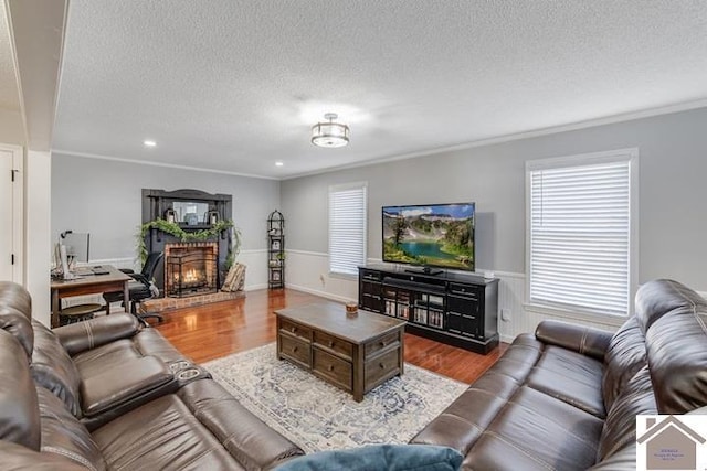 living room with hardwood / wood-style floors, crown molding, a textured ceiling, and a brick fireplace