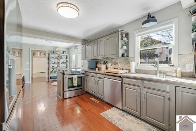 kitchen featuring stainless steel appliances, dark hardwood / wood-style floors, decorative backsplash, and gray cabinetry