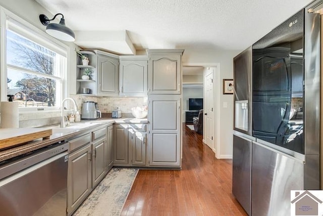 kitchen with dishwasher, gray cabinetry, dark hardwood / wood-style flooring, and decorative backsplash