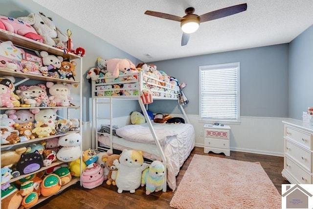 bedroom featuring ceiling fan, dark hardwood / wood-style flooring, and a textured ceiling