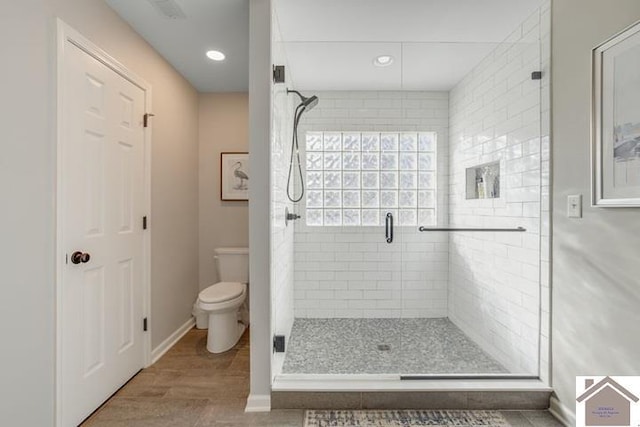 bathroom featuring a shower with shower door and toilet