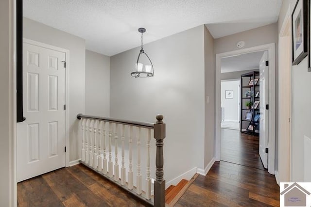 hall with dark wood-type flooring and a textured ceiling