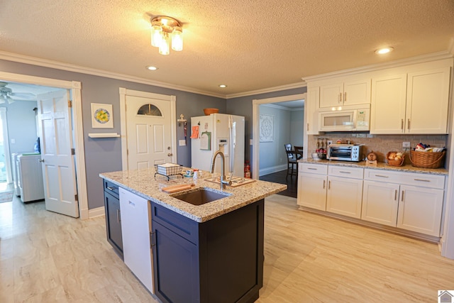 kitchen featuring backsplash, crown molding, white appliances, white cabinetry, and a sink